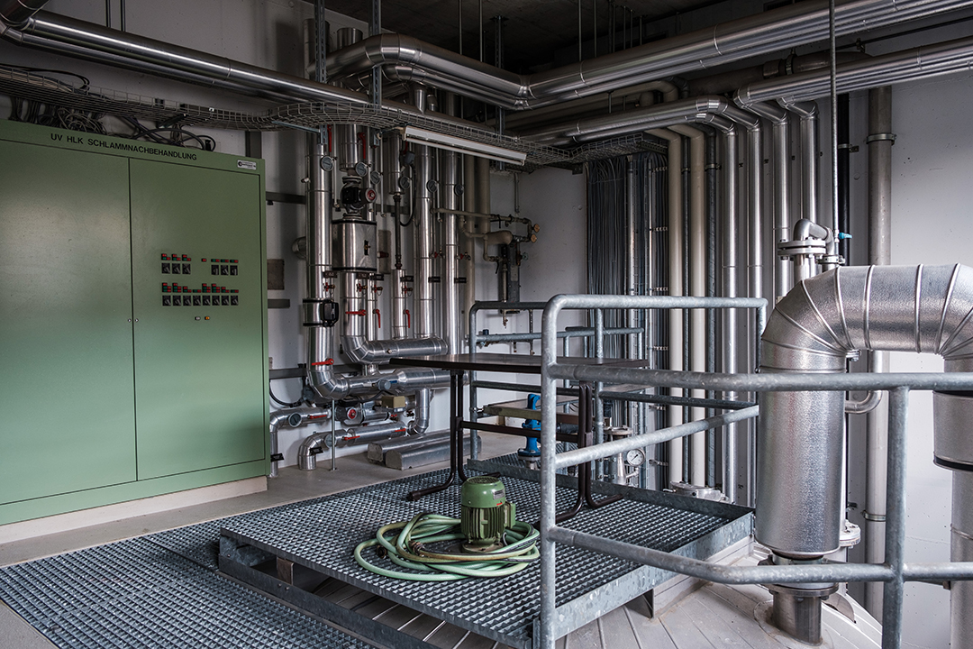 Korridor der ARA Gürbetal. An den Wänden sind Rohre und Wasserleitungen fixiert.